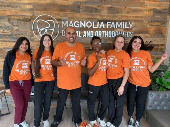 Magnolia Family Dental and Orthodontics team wearing orange Bullying Bites campaign shirts inside the dental office in Magnolia, TX